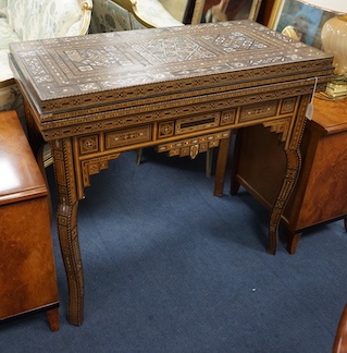 A 19th century Damascus mother of pearl, bone, and marquetry inlaid folding games table, with card, backgammon and chess surfaces, width 94cm, depth 47cm, height 85cm